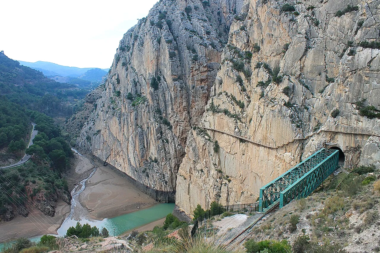 La passerella sulla parete rocciosa sopra il ponte ferroviario verde e il bacino