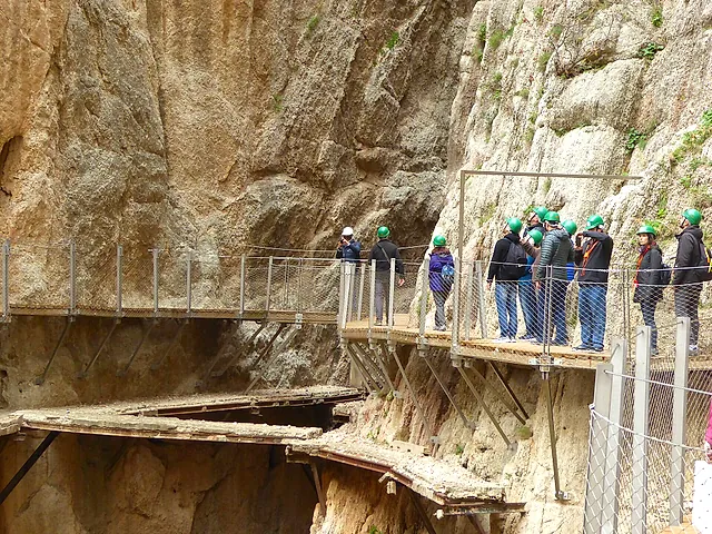 Visitatori con il casco sulle passerelle in alto sulla parete del canyon